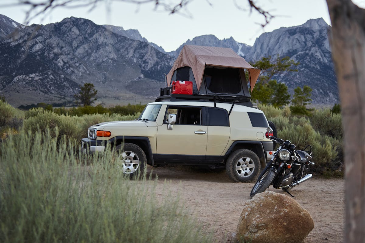 a motorcycle and a white vehicle with a camping setup